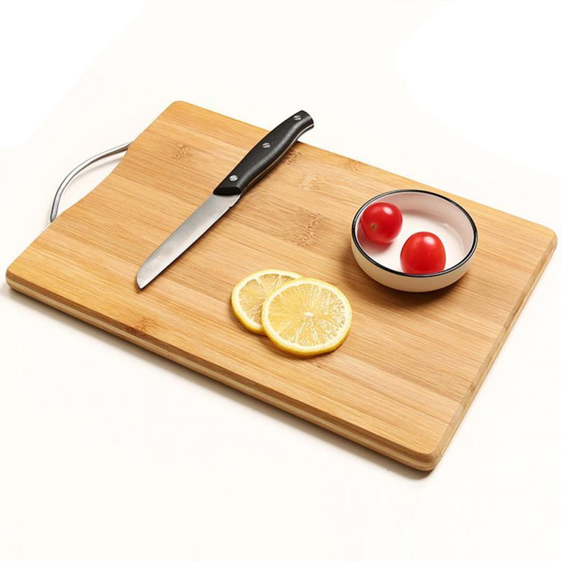 Wooden cutting board with knife, lemon slices, and cherry tomatoes on a white surface.