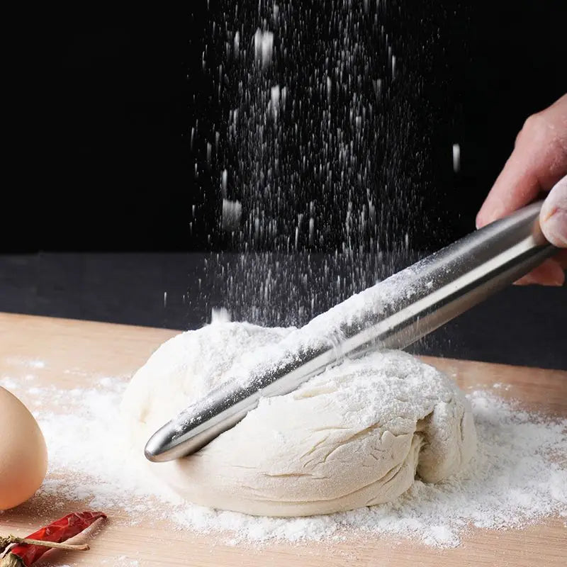 person smacking dough down with a small steel rollin pin on a wooden board