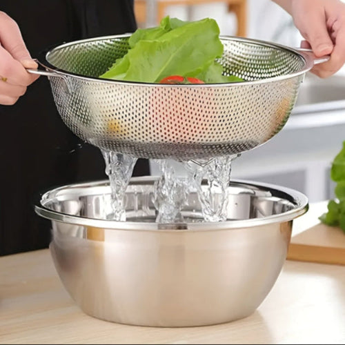 Person using a metal colander to drain water from vegetables into a bowl.