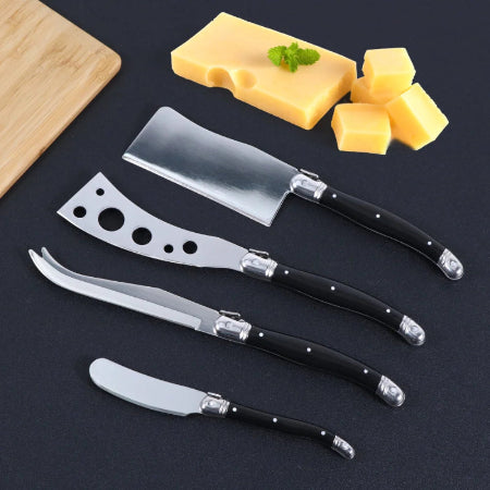 Set of cheese knives with black handles on a dark surface, accompanied by cheese and a cutting board.