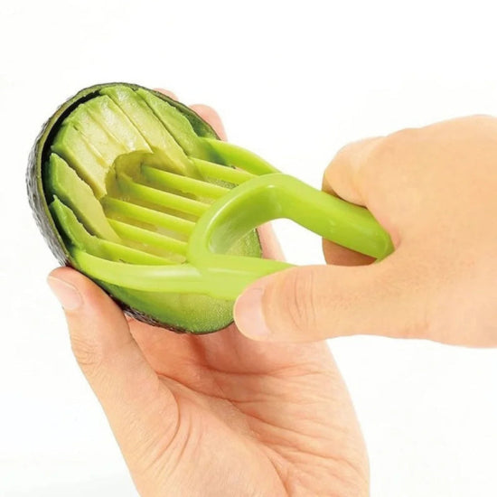 person slicing avocado flesh with a green plastic slicer tool