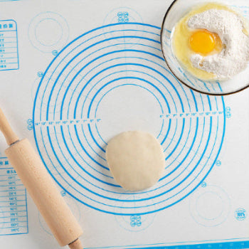 Blue and White Dough Rolling Mat with Measurement Guides a wooden rolling pin, piece of dough and an egg in a bowl