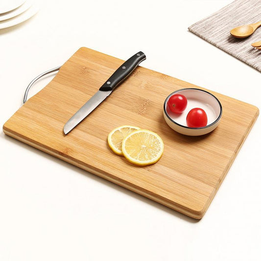 Wooden cutting board with knife, lemon slices, and cherry tomatoes on a white surface.