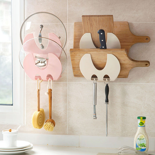 pink and white wall mounted kitchen storage racks with pot lids, chopping boards and utensils