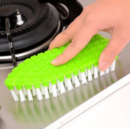 person cleaning a stove top with a green scrubbing brush