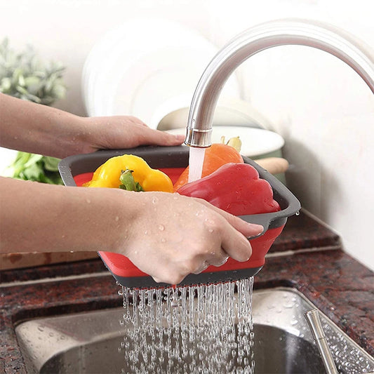 Person using a collapsible silicone vegetable scrubber to wash vegetables under running water in a kitchen sink.