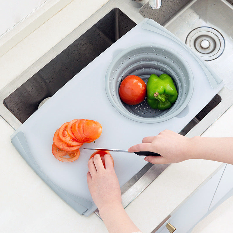 person cutting vegetables over a sink and on a white cutting board