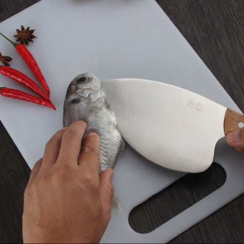 person filleting fish on a silver cutting board with a fish filleting knife