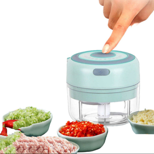 Food chopper with a finger pressing a button, surrounded by chopped vegetables 