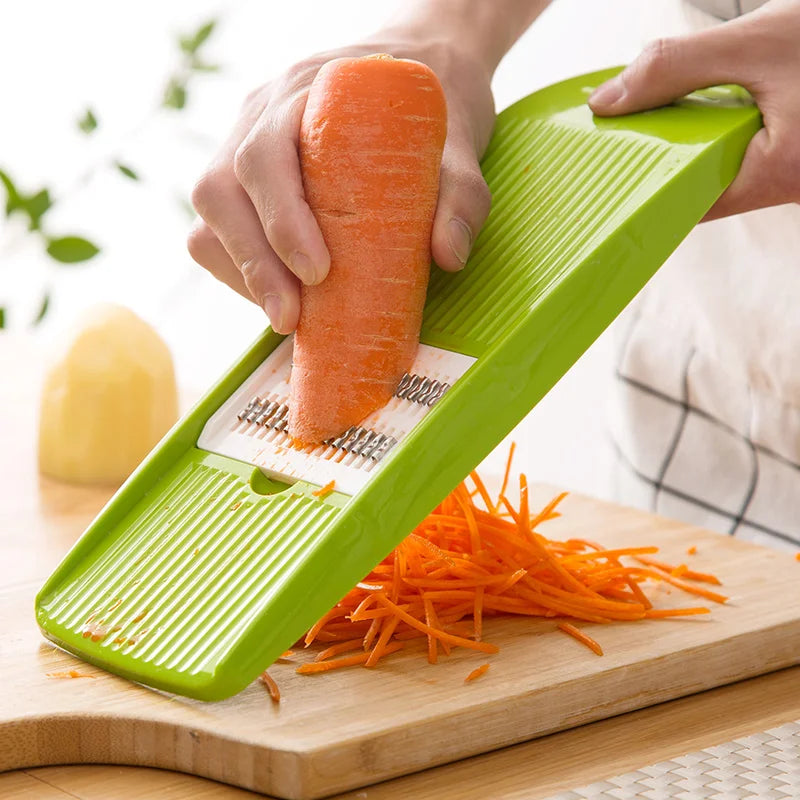 person grating carrot with a green mandolin