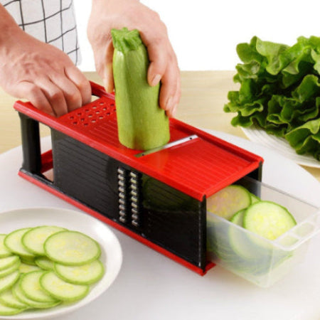person slicing zuchinni on a red grater, slicer box with a clear compartment