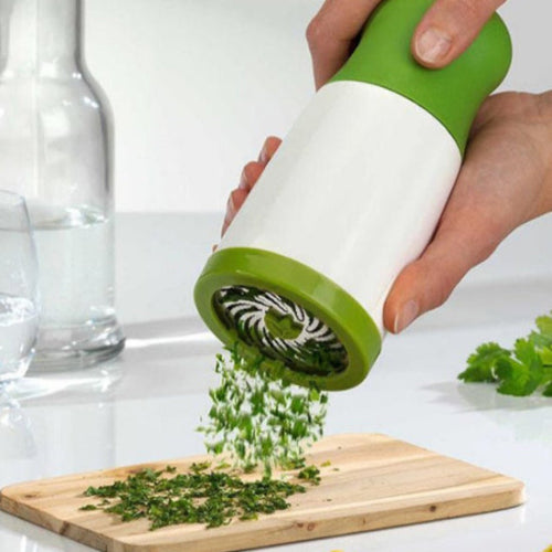 person with a green and white herb grinder grinding herbs onto a wooden board