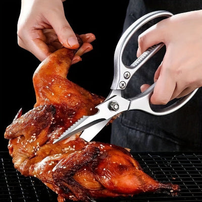Person using kitchen shears to cut into a roasted chicken on a black background