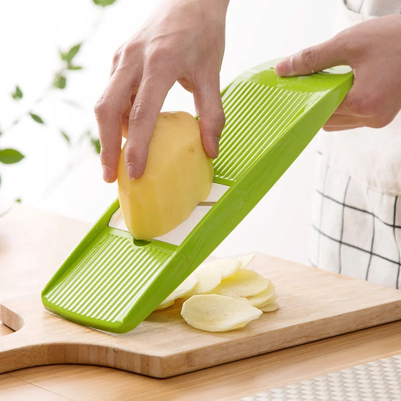 person slicing potatoes with a green mandolin slicer