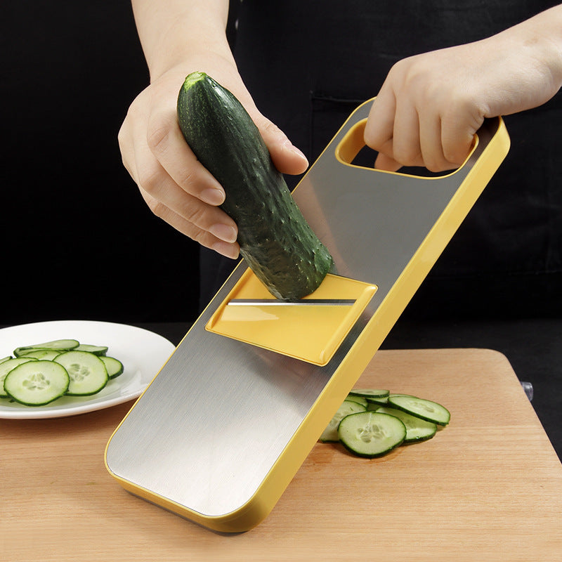 Person using a yellow mandolin slicer to cut cucumber on a wooden cutting board.