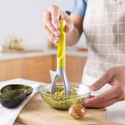 person mashing avocado with a green and grey mashing tool