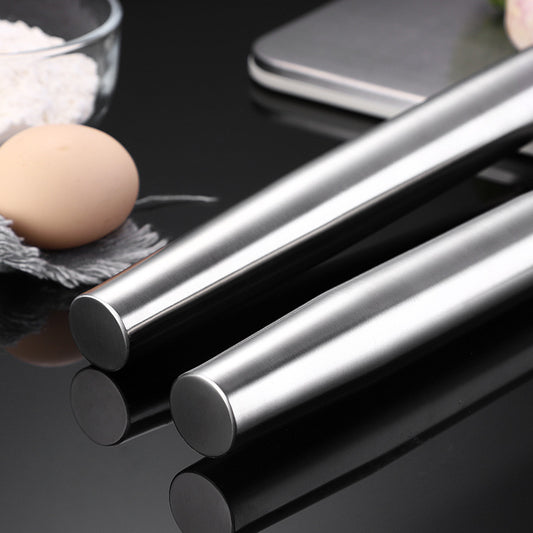 Two metal rolling pins with an egg and glass bowl in the background.