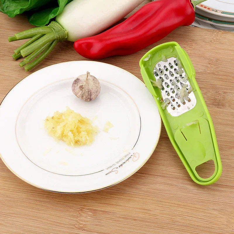 green mini grater tool with a dish of grated garlic and a red pepper in the background