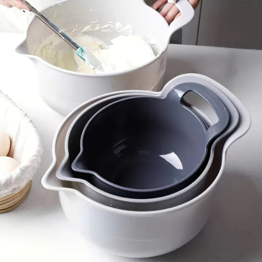 Set of mixing bowls with a spatula and ingredients on a kitchen counter