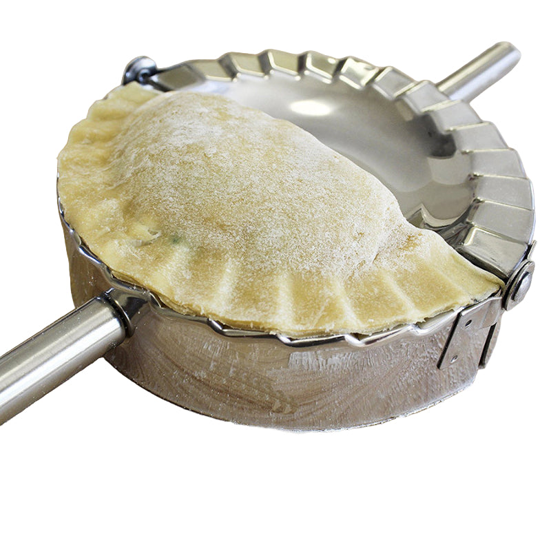 Pie crust being shaped with a metal pie dough press on a white surface.
