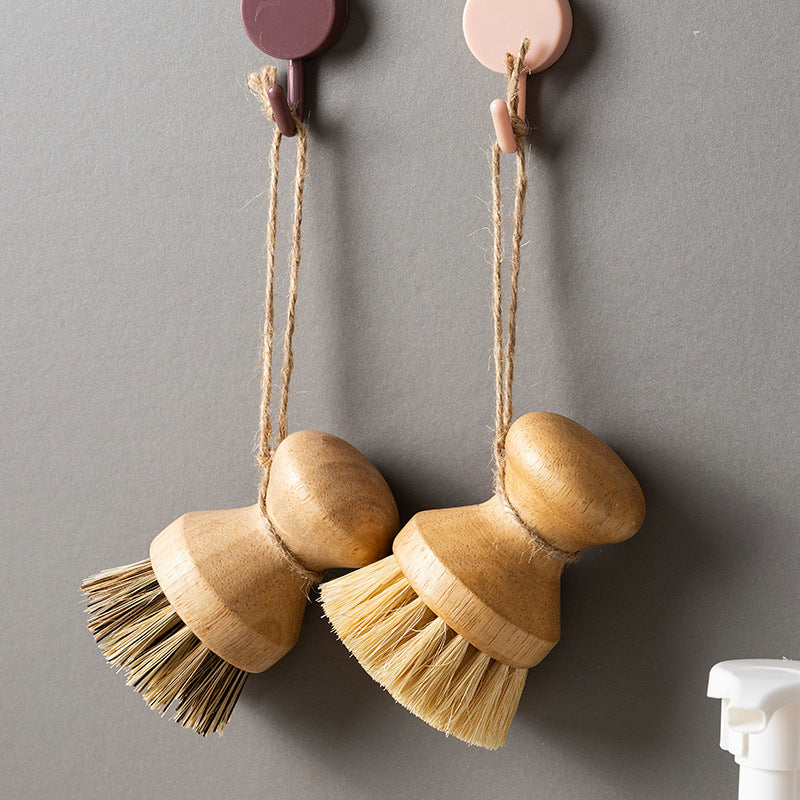 Two wooden cleaning brushes hanging on a gray wall with hooks.