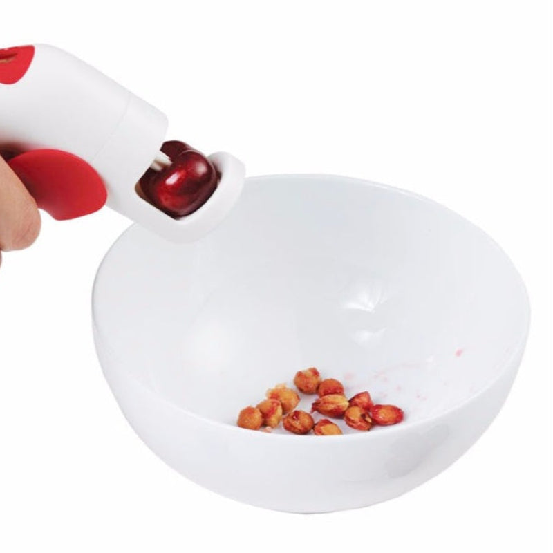 person pitting cherries with pips in a white bowl