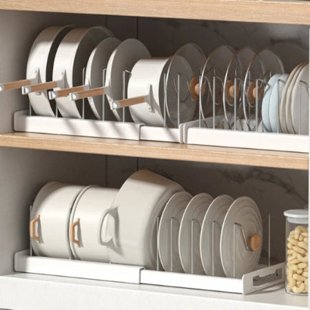 white expandable pot racks in a kitchen cabinet with pots, pans and lids