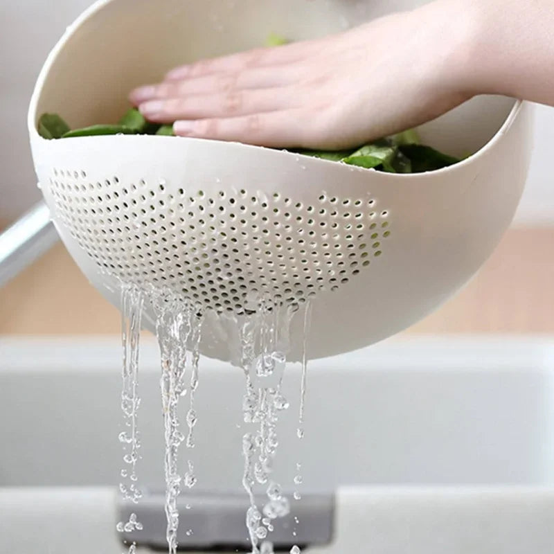 Person washing vegetables in a white colander over a sink