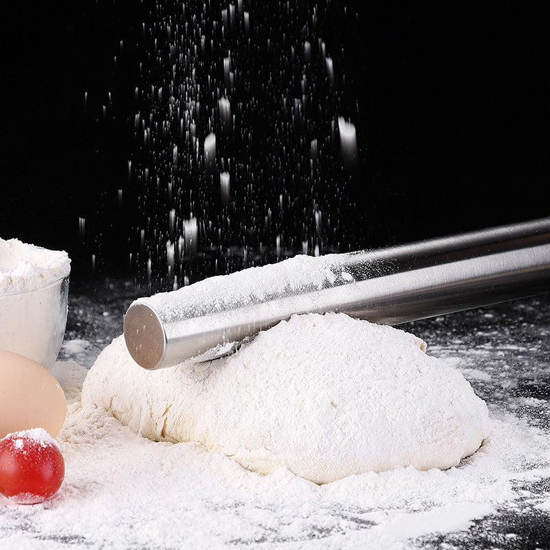 Rolling pin on a ball of dough with flour and an egg on a dark surface