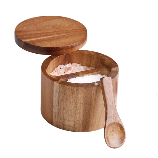 Wooden container with lid and spoon filled with pink salt on a marble surface.