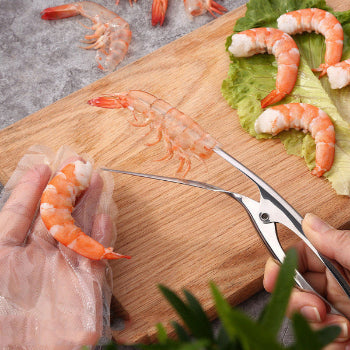stainless steel shrimp peeler with shrimps and lettuce on a wooden board