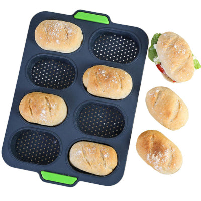 black with green handles silicone bread roll baking mould with four bread rolls in it and three outside of it