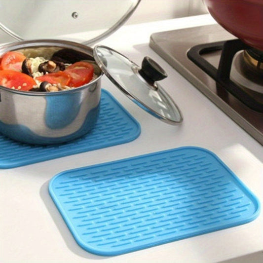 Blue silicone mats on a kitchen countertop with pots of food.