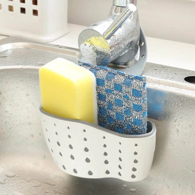 white silicone kitchen sink caddy connected to a faucet with a yellow sponge and a blue grey cloth