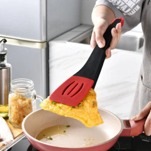 red and black 3-in-1 silicone kitchen spatula & tongs lifting an omelete in a pan