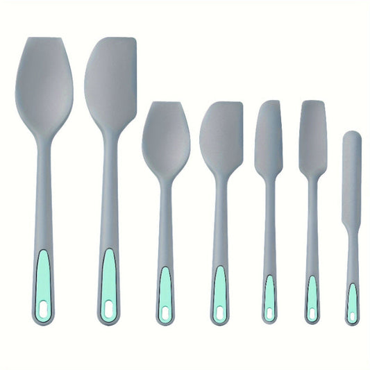 Set of gray spatulas with green handles on a white background