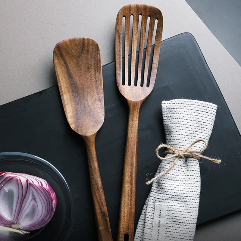 Two wooden spatulas and a white cloth on a dark surface with a gray background.