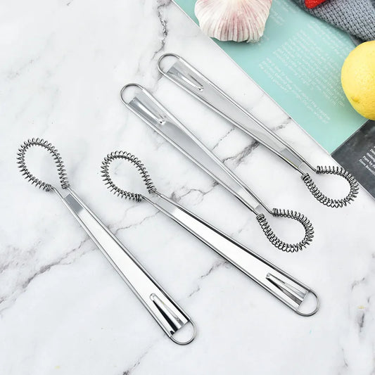 Set of four metal egg whisks on a marble surface