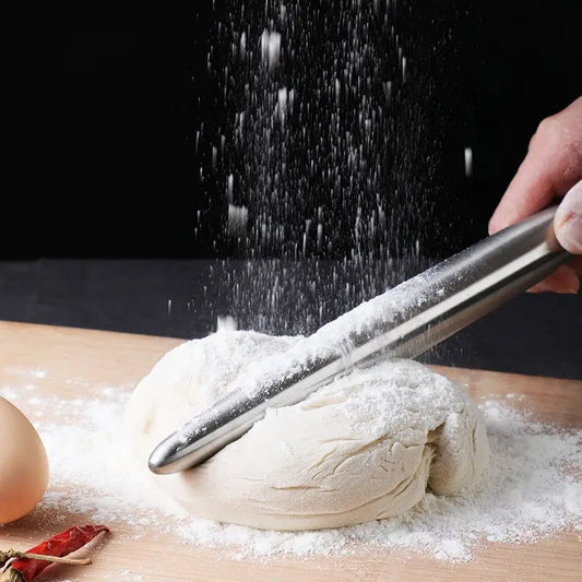 person smacking dough down with a small steel rollin pin on a wooden board