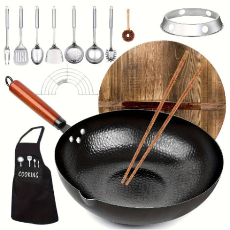 Black wok with wooden handle, black apron, wooden cutting board with chopsticks, and various kitchen utensils on a white background.