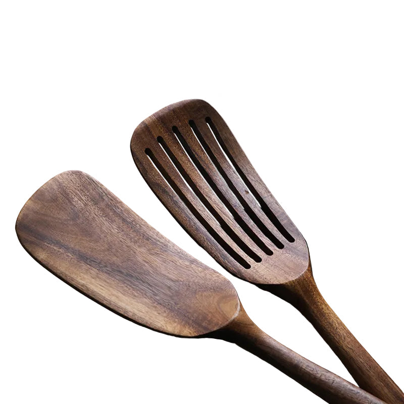 Three wooden spatulas on a gray surface with a metal lid in the background.